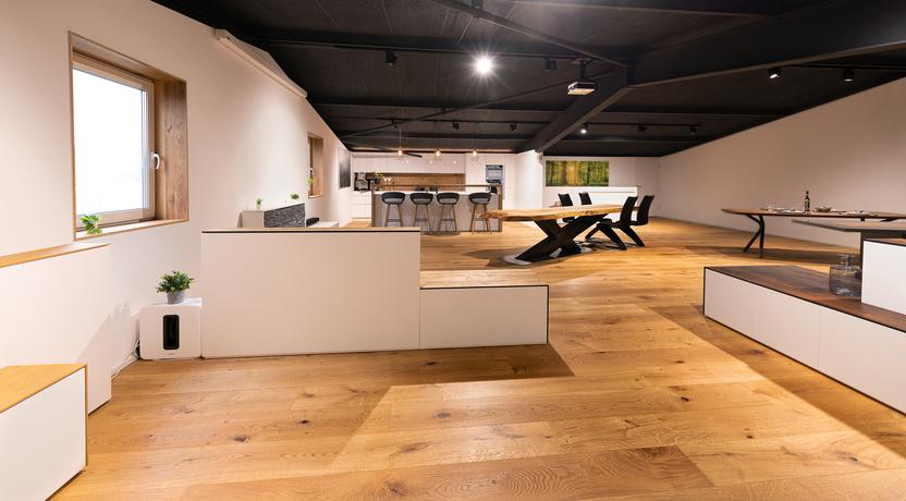 Loft-Wohnraum mit motorisierten Möbeln Geräumiges Loft mit offener Küche, Esstischen und motorisierten Möbeln, natürlichen Holzböden und moderner Beleuchtung.