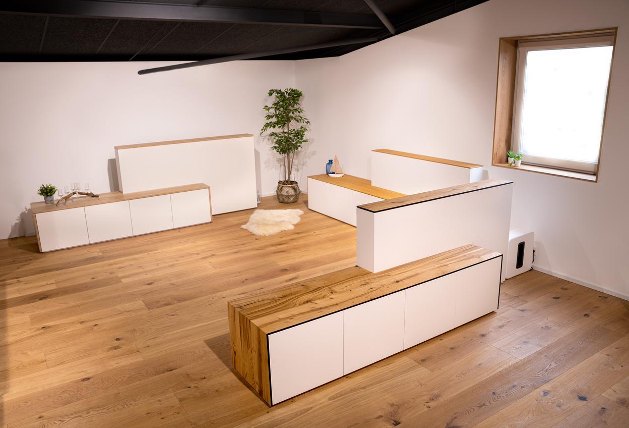 Ausstellung motorisierte Möbel Mehrere weiße Sideboards mit Holzoberfläche und integriertem TV-Lift in modernem Showroom.