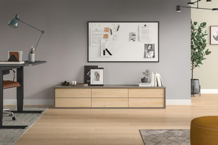 Elegantes Zimmer mit massgefertigtem Sideboard Wohnraum mit hellem, massgeschneidertem Sideboard aus Holz, darüber eine Pinnwand und Dekorationen.