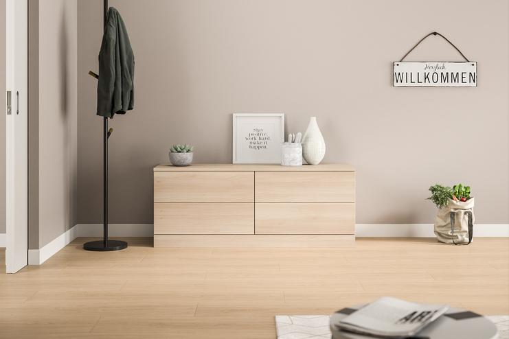 Massgefertigte, helle Kommode im modernen Eingangsbereich. Eine schlichte, massgeschneiderte Kommode in hellem Holzdekor mit glatten Fronten, harmonisch integriert in den einladenden Eingangsbereich eines Hauses.