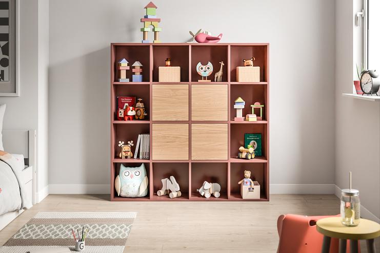 Farbenfroher, massgefertigter Spielzeugschrank im Kinderzimmer. Ein Schrank nach Mass in Terrakottafarbe mit offenen und geschlossenen Fächern, befüllt mit Spielzeug und Büchern, bietet spielerische Ordnung im Kinderzimmer.