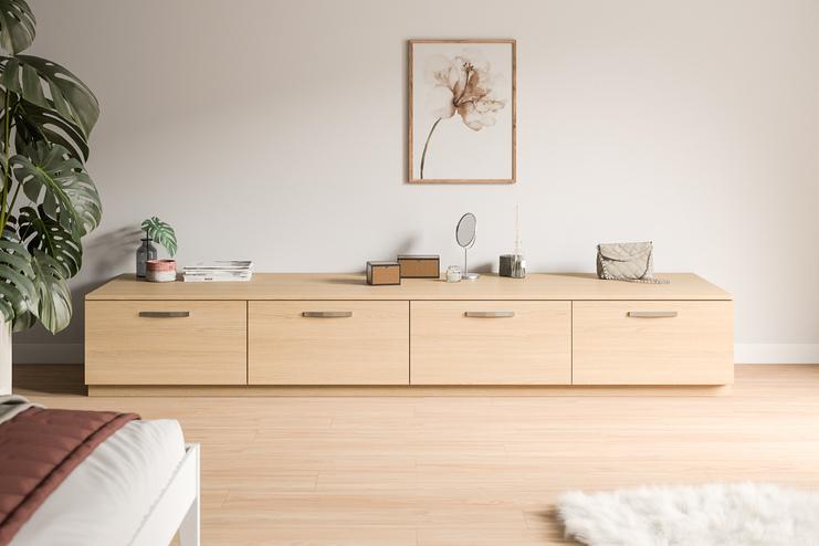 Modernes Sideboard nach Mass in einem minimalistischen Zimmer Ein massgeschneidertes Sideboard aus hellem Holz mit dekorativen Gegenständen und einer Pflanze in einem schlichten Raum.