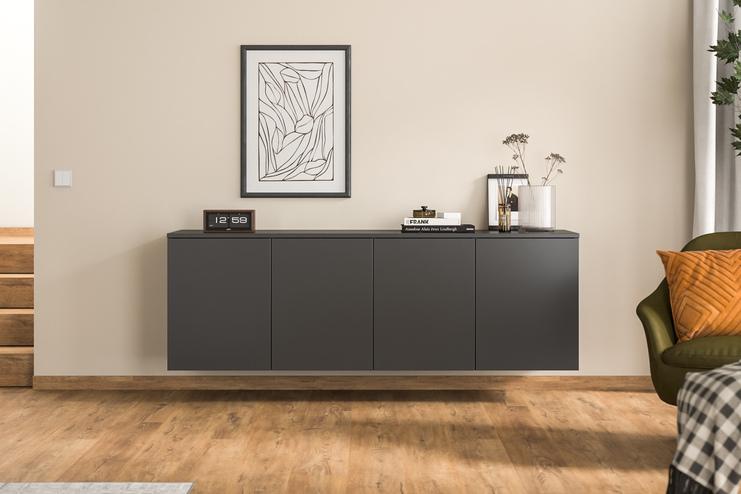 Massgefertigtes Hängeboard in modernem Wohnzimmer Ein massgeschneidertes Hängeboard in Anthrazit ergänzt den Wohnraum, stilvoll unter einem abstrakten Gemälde und neben einer grünen Samtsessel platziert.