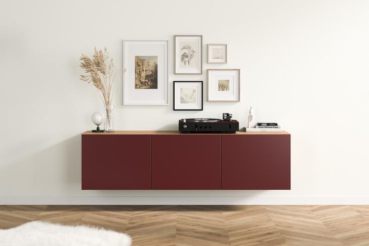 Modernes Hängeboard nach Mass im Wohnraum Elegantes, burgunderrotes Hängeboard nach Mass mit glatten Fronten und Holzakzenten, angebracht unter einer kunstvollen Bildergalerie im Wohnzimmer.