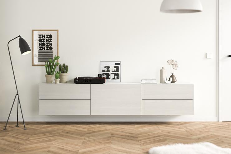 Helles Hängeboard nach Mass im modernen Wohnzimmer Ein massangefertigtes, wandmontiertes Hängeboard in schlichtem Weiss, ergänzt durch zeitgenössische Deko und Grünpflanzen, fügt sich nahtlos in ein gemütliches Wohnambiente ein.