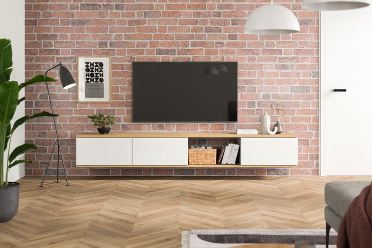 Stilvolles Hängeboard nach Mass an einer Backsteinwand Massangefertigtes Hängeboard in Weiss, minimalistisch gestaltet, unter einem Wandfernseher, vor einer roten Backsteinwand, ergänzt durch Pflanzen und Bücher.