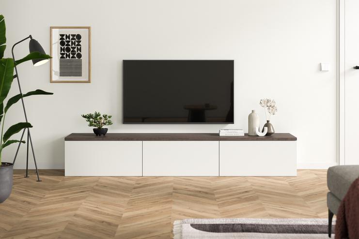 Massgeschneiderte Kommode in schlichtem Design als TV-Unterschrank Zeitgenössische Kommode nach Mass mit weissen und dunklen Holzelementen im Wohnbereich dient als stilvoller Unterschrank für einen Flachbildfernseher.