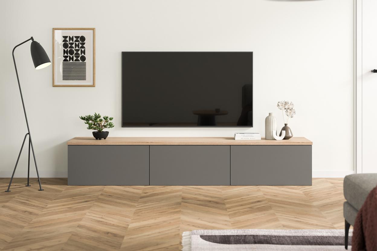 Elegante Kommode nach Mass im modernen Wohnzimmer Massgefertigte, dunkelgraue Kommode unter einem Flachbildfernseher, kombiniert mit einer warmen Holzplatte, minimalistischer Dekoration und einem schwarzen Stehlampe daneben.